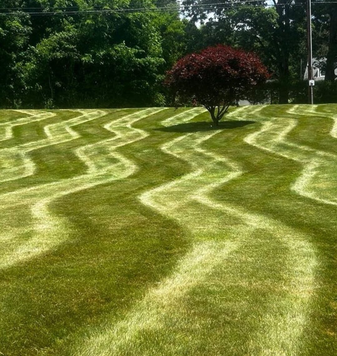 Decorative wave mowing patterns on a lush green residential lawn maintained by Four Seasons Property Maintenance in Western Massachusetts