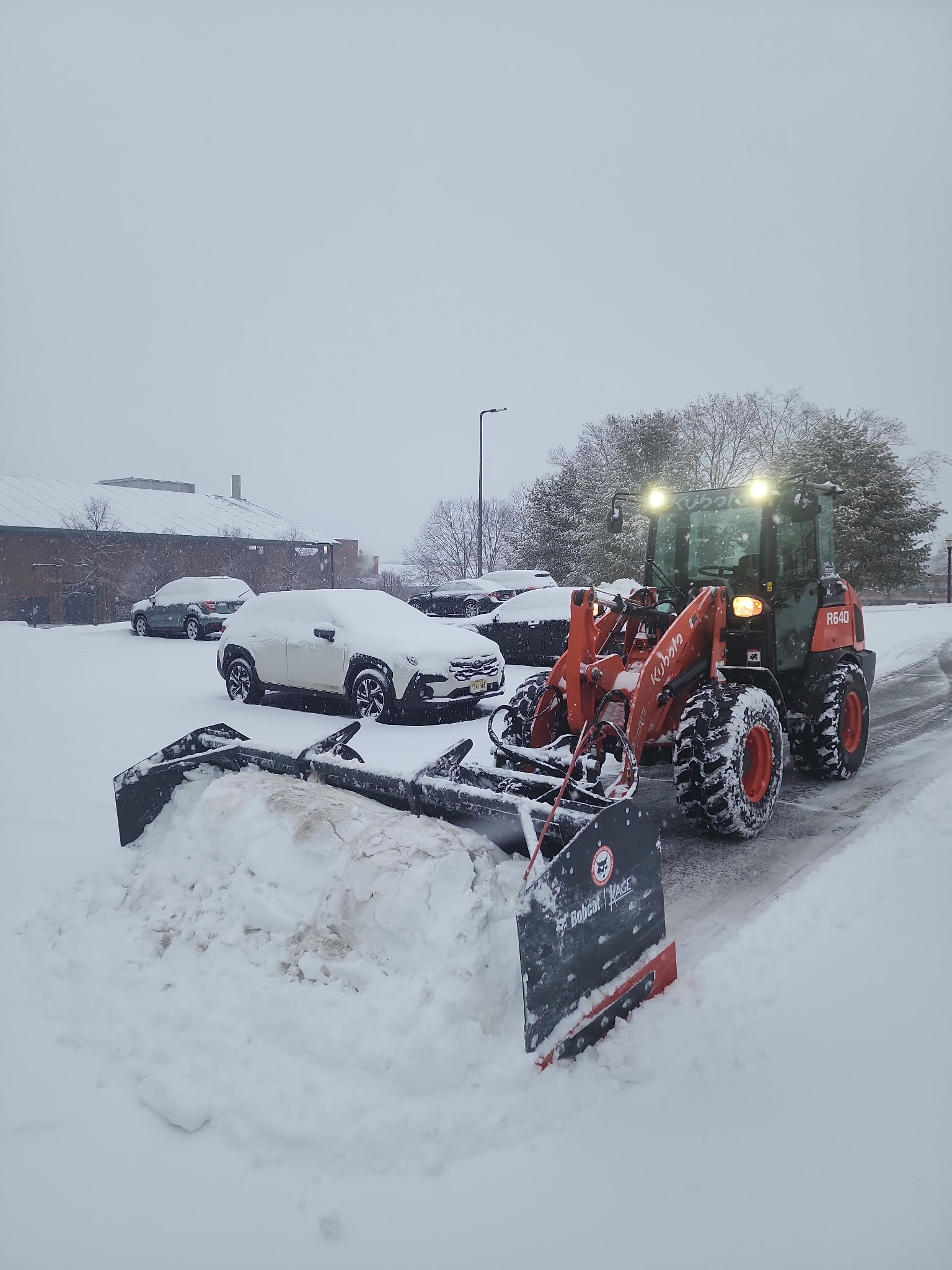 Four Seasons Property Maintenance tractor with bucket attachment removing snow on a residential property in Western Massachusetts